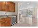 Kitchen wet bar with wooden cabinets and stainless steel cooler, leading into a bright dining area with backyard view at 1155 Phillip Island St, Henderson, NV 89052