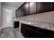 Functional laundry room with dark wood cabinets, granite countertop and sink, offering ample storage space at 11952 Girasole Ave, Las Vegas, NV 89138