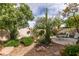 Landscaped backyard featuring a patio, seating area, desert plants, and mature trees, creating a serene outdoor oasis at 1632 Royal Canyon Dr, Las Vegas, NV 89128