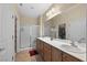 Well-lit bathroom with double sinks, walk-in shower, and a large mirror at 2467 Moonlight Valley Ave, Henderson, NV 89044