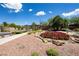 Picturesque community entrance with stone pillars, desert landscaping, and vibrant red flowering plants at 2467 Moonlight Valley Ave, Henderson, NV 89044