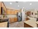 Well-equipped kitchen with stainless steel appliances, wooden cabinets, tile floors, and neutral countertops at 2467 Moonlight Valley Ave, Henderson, NV 89044
