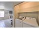 Laundry area with side by side washer and dryer, adjacent to living area with tile floors and a window at 2595 Amber Crest St, Las Vegas, NV 89142