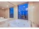 Bright bathroom featuring a soaking tub, tile surround, and a large window with a city view at 322 Karen Ave # 2807, Las Vegas, NV 89109