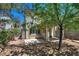 Private backyard with a patio, lush greenery, shade trees, and rock landscaping at 4487 Tomer Ln, Las Vegas, NV 89121