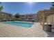 Community pool surrounded by a brick patio and lush landscaping on a sunny day at 7200 Pirates Cove Rd # 2084, Las Vegas, NV 89145