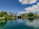 Scenic community lake view with lush landscaping and palm trees under a bright blue sky with fluffy clouds at 8140 Bay Harbor Dr, Las Vegas, NV 89128