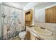 Bathroom with a daisy shower curtain, wooden cabinet, and large mirror at 960 Third St, Pahrump, NV 89048
