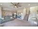 Open concept living area featuring plush carpeting, ceiling fan, and seamless flow to kitchen and entryway at 10031 Fletcher Peak Ave, Las Vegas, NV 89178