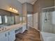 Bathroom featuring dual sinks, mirrors, a walk-in shower, and wood look floors at 10279 Montes Vascos Dr, Las Vegas, NV 89178