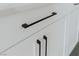Detailed close-up of modern white kitchen cabinetry featuring sleek, matte black hardware pulls at 11173 Concord Valley Dr, Las Vegas, NV 89135