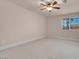 Spacious bedroom with neutral carpet, walls, ceiling fan, and a large window at 1312 Fragrant Spruce Ave, Las Vegas, NV 89123