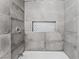 Close-up of shower with gray tile and a decorative shelf at 1415 Helen Ave, North Las Vegas, NV 89030