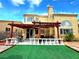 Backyard with a covered patio, manicured lawn, and multiple windows at 1628 Palmae Way, Las Vegas, NV 89128