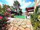 Landscaped backyard with vibrant pink flowers, a pergola, and stone pathway at 1628 Palmae Way, Las Vegas, NV 89128