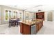 Kitchen island with sink, granite countertops, and seating in an open concept kitchen and dining area at 2 Lago Turchino Ct, Henderson, NV 89011