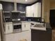 Updated kitchen with stainless steel appliances, white cabinetry, and dark backsplash at 23 Indian Run Way, Las Vegas, NV 89148