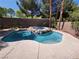Backyard oasis featuring a sparkling pool with a rock-enclosed hot tub and mature landscaping at 23 Indian Run Way, Las Vegas, NV 89148