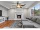 Bright living room featuring a cozy fireplace, hardwood floors, and a ceiling fan at 644 Wind Cave Ct, Henderson, NV 89012