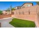 Enclosed backyard with artificial turf, concrete patio, and string lights overhead at 7345 Chesapeake Cove St, Las Vegas, NV 89166