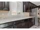 Kitchen showing granite counters, dark wood cabinetry, and stainless steel refrigerator at 7345 Chesapeake Cove St, Las Vegas, NV 89166