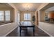 Bright dining room with a modern light fixture, dark wood table, and adjacent kitchen space at 9032 Retro Ct, Las Vegas, NV 89149