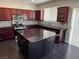 Open kitchen with large island, granite counters, stainless appliances and dark wood cabinets at 10118 Farmington Hall Ct, Las Vegas, NV 89129