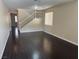 Open-concept living room with dark wood floors, a staircase, and natural light from a window at 10118 Farmington Hall Ct, Las Vegas, NV 89129
