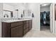 Bathroom with double sinks, granite countertop, dark cabinetry, and walk-in closet at 1266 Smokey Valley Ln, Henderson, NV 89002