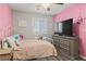 Comfortable bedroom with a pink accent wall, plantation shutters, and modern furniture at 1266 Smokey Valley Ln, Henderson, NV 89002