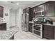 Modern kitchen with stainless steel appliances, dark wood cabinets, and tile flooring at 1266 Smokey Valley Ln, Henderson, NV 89002