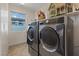 Modern laundry room with stainless steel washer and dryer and a view to the outdoors at 1266 Smokey Valley Ln, Henderson, NV 89002