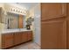 Bathroom with wood cabinetry, white countertops, and large mirror with decorative lighting at 2033 Summer Spruce Pl # 102, Las Vegas, NV 89134