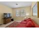 Cozy living room with neutral walls, plush red sofa, and area rug near bright window at 2033 Summer Spruce Pl # 102, Las Vegas, NV 89134