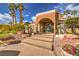 Exterior view of the clubhouse entrance with desert landscaping, flower pots, rocks, and palm trees at 2120 Ramrod Ave # 2216, Henderson, NV 89014