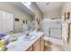 Well-lit bathroom featuring a single sink vanity, framed mirror, and glass-enclosed shower-tub combination at 2522 Darda St, Henderson, NV 89044