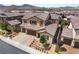 Aerial view of a two-story home featuring a tile roof, three-car garage, and landscaped front yard at 2575 Hazelburn Ave, Henderson, NV 89044