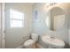 Cozy powder room with a pedestal sink, round mirror, and window providing natural light at 3312 Speckle Summer Pl # 3, North Las Vegas, NV 89084