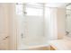 Bright white tiled tub and shower combination featuring a shower head and arched window for natural light at 3312 Speckle Summer Pl # 3, North Las Vegas, NV 89084