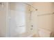Bright white tiled tub and shower combination featuring a shower head and storage shelves at 3312 Speckle Summer Pl # 3, North Las Vegas, NV 89084