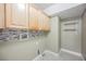 Functional laundry room with tiled backsplash, utility connections, and built-in shelving at 3312 Speckle Summer Pl # 3, North Las Vegas, NV 89084