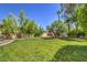 Large backyard with a well-manicured lawn, mature trees, and a play structure at 605 Canyon Greens Drive Dr, Las Vegas, NV 89144