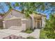 Close up of the exterior, showcasing the front door, a two car garage, and a landscaped yard at 8242 Tribute Ln, Las Vegas, NV 89147