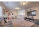 Spacious living room with carpeting, fan lights, wall-mounted TV, and comfortable couches at 9208 S Park St, Las Vegas, NV 89178