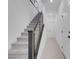 Modern staircase with gray carpet, metal handrail, and white walls, creating a sleek transition between levels at 10292 Fragrant Apple Ct, Las Vegas, NV 89141