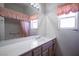 Bathroom featuring a large mirror, vanity, and charming pink window covering at 10628 Mission Lakes Ave, Las Vegas, NV 89134