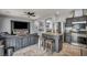 Cozy living room with modern TV, gray sectional sofa, and breakfast bar with granite countertop and stools at 10952 Napa Ridge Dr, Las Vegas, NV 89144