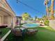 Inviting backyard with a shimmering pool, patio seating, and lush artificial turf at 1704 Cordoba Canyon St, Las Vegas, NV 89117