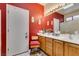 A bright bathroom features a wide mirror, vanity, and red accent wall at 2120 Desert Woods Dr, Henderson, NV 89012