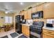 Efficient kitchen featuring classic oak cabinets, black appliances, and an adjoining dining area for casual meals at 2120 Desert Woods Dr, Henderson, NV 89012